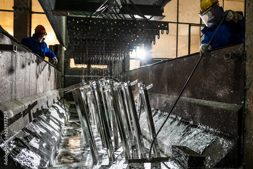 People at work galvanizing metallic structures in a zinc bath