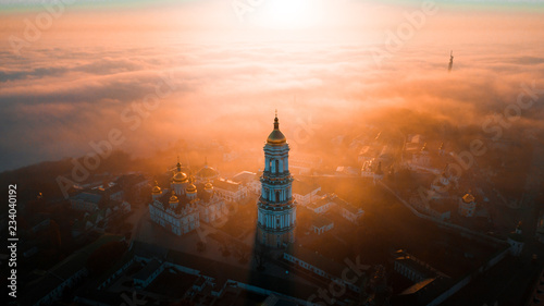 Aerial view of Kiev Pechersk Lavra at dawn and the city covered with thick fog in the background.