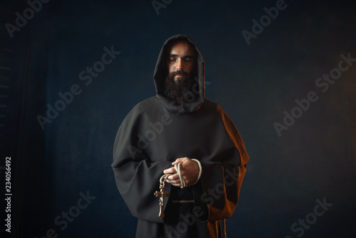 Medieval monk holds cross in hands and praying