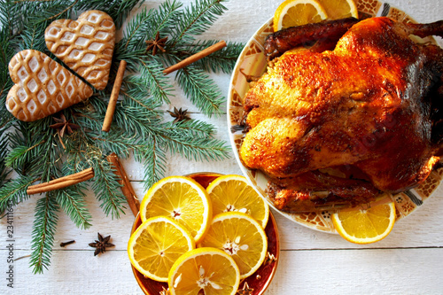 Pieczona kaczka z pomarańczami otoczona gałązkami świerku, piernikami i gwiazdkami anyżu, świąteczny obiad w Boże Narodzenie