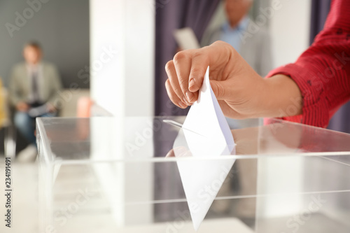 Woman putting ballot paper into box at polling station, closeup