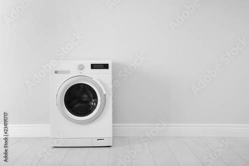 Washing machine near white wall, space for text. Laundry day