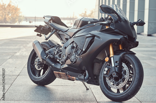 Close-up photo of a black superbike outside near building.