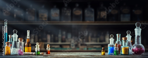 Vintage medications in small bottles on wood desk. Old medical, chemistry and pharmacy history concept background. Retro style.