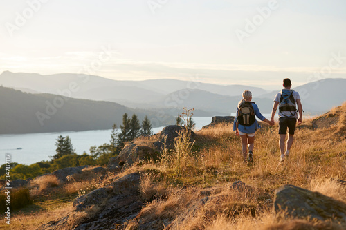 Rear View Of Couple Walking On Top Of Hill On Hike Through Countryside In Lake District UK