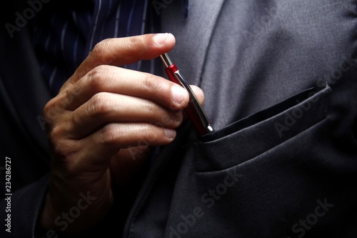 Man inserting a pen to his suit's pocket