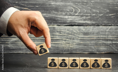 Businessman puts a block with a picture of dollars. The capital accumulation and successful business. Increased budget and profits in the team. Increase investment fund. Saving money. Economic boom