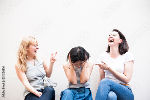 Cupple caucasian women laughing and looking asian woman ,who confused and take their hands off the head, insolvent business ,unsuccessful business concept.