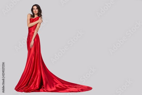 Beauty young woman in fluttering red dress. Gray background.