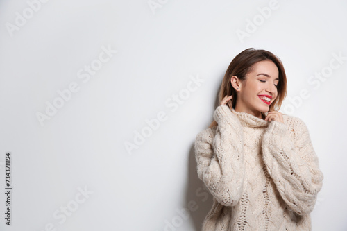Beautiful young woman in warm sweater on white background. Space for text