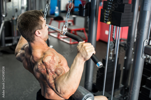 Shoulder pull down machine. Fitness man working out lat pulldown training at gym. Upper body strength exercise for the upper back.