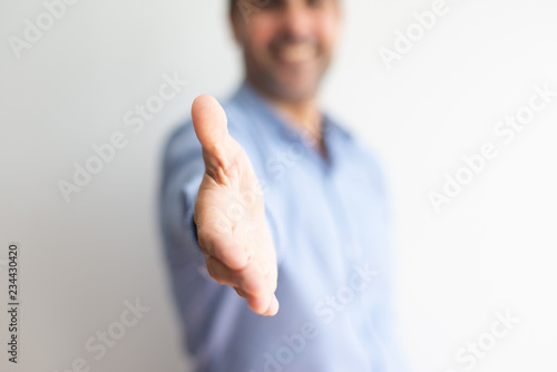 Closeup of business man offering hand for handshake. Entrepreneur greeting you. Deal concept. Cropped front view.