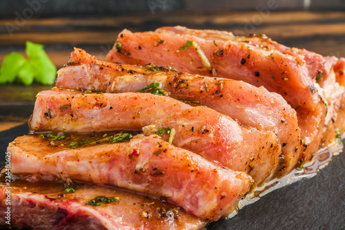 Raw pork fillet marinated with pepper, salt, fresh parsley, honey, paprika, cumin on black stone board