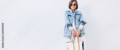 Elegant woman dressed in oversize denim jacket and wide white trousers