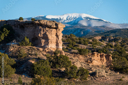 Sandstone red rock formation with the snow-capped peaks of the Sangre de Cristo mountain range in the distance near Santa Fe, New Mexico