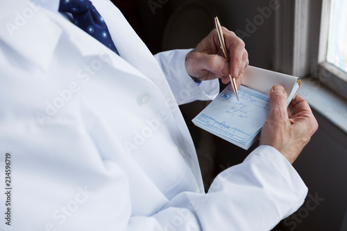 A doctor writing a prescription on a blue prescription pad.