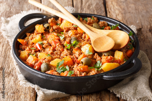 Beef Picadillo cooked with potatoes, carrots, raisins, olives and spices close-up in a frying pan. horizontal
