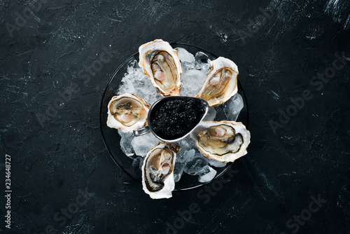 Oysters and black caviar in a plate of ice and lemon. Seafood. Top view. Free copy space.