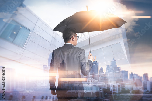 The double exposure image of the Businessmen are spreading umbrella during sunrise overlay with cityscape image. The concept of modern life, business, insurance and protection.