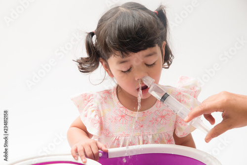 Asian mother making nasal wash for her baby girl by flushing kid'nose with syringe and saline. An Irrigation can benefit people who have sinus problems,nasal allergies isolated on white background