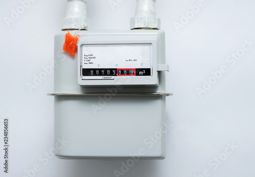 A gas meter on the white wall. Counter for distribution natural gas.