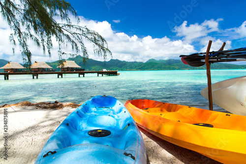kayaking, leisure, water sport and summer holidays concept - canoes or kayaks moored on beach in french polynesia