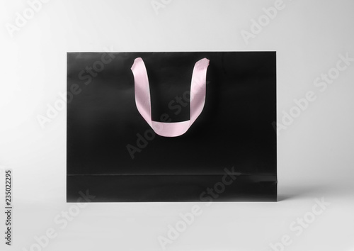Paper shopping bag with ribbon handles on white background. Mockup for design