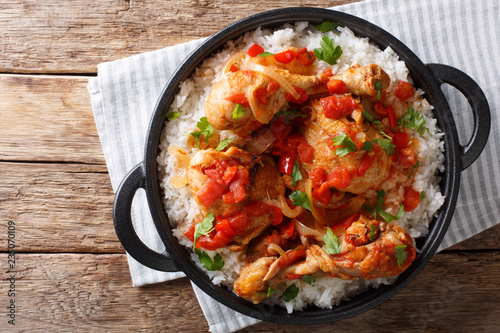 Haitian Stewed Chicken (Poule en Sauce)served with white rice in a black pan closeup. Horizontal top view