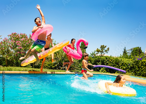 Happy friends jumping in pool on the vacations