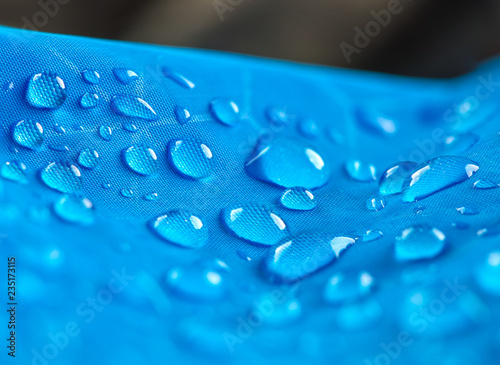 Water drops on waterproof nylon fabric. Macro detail view of texture of blue woven synthetic waterproof clothing. Waterproof fabric with water drops. Rain Drops on Water Resistant Textile.