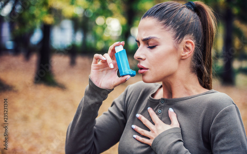 Young woman treating asthma with inhaler