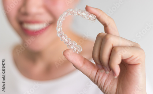 A smiling woman holding invisalign or invisible braces, orthodontic equipment