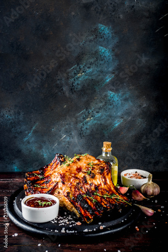 Grilled meat concept. bbq pork ribs with barbeque sauce, olive oil. fresh herbs on dark wooden background copy space