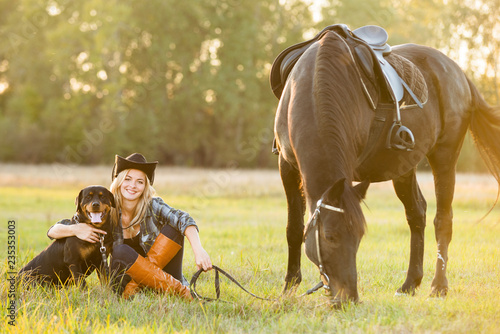 Girl horse rider sitting with a dog near the horse and hugs the horse. Horse theme