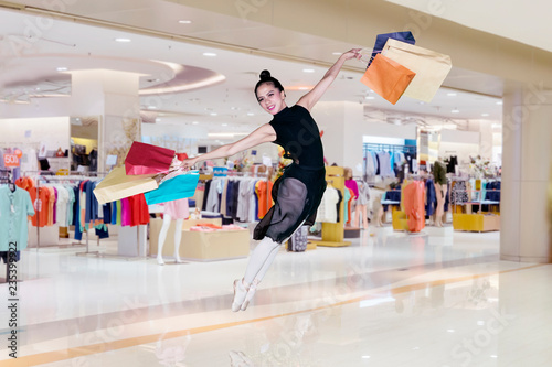 Ballerina leaping with shopping bags in the mall