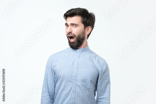 Young funny hispanic man with black beard is shocked and suprised. Burping or bad manners.