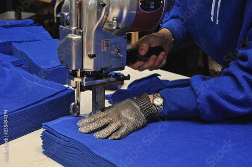 commercial textiles worker cutting a pile of fabric