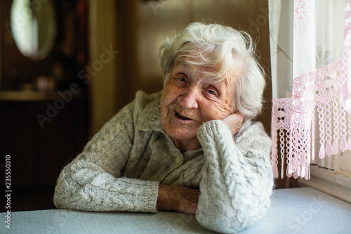 Portrait of elderly pensioner lady sitting at the table.