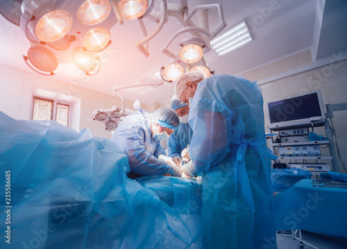 Process of trauma surgery operation. Group of surgeons in operating room with surgery equipment.