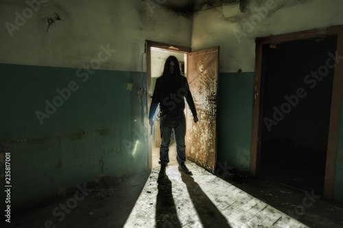 Serial killer maniac with knife in dark abandoned building. Maniac thriller concept