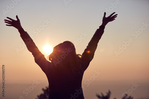 Woman with arms wide open enjoying the sunrise / sunset time.