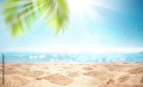 Abstract blur defocused background, nature of tropical summer beach with rays of sun light. Golden sand beach, sea water and palm leaves against sky. Copy space, summer vacation concept.