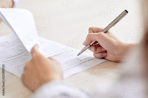 Crop shot of person with pen signing contract at desk in daylight