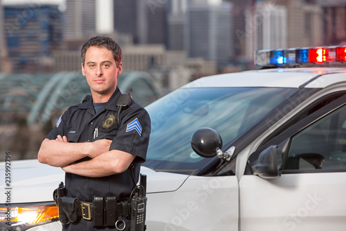 Police sergeant leaning agains car