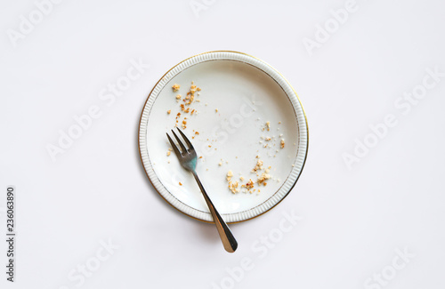 Empty plate with crumbs after eating on a white background. The concept of the end of the holiday or celebration.