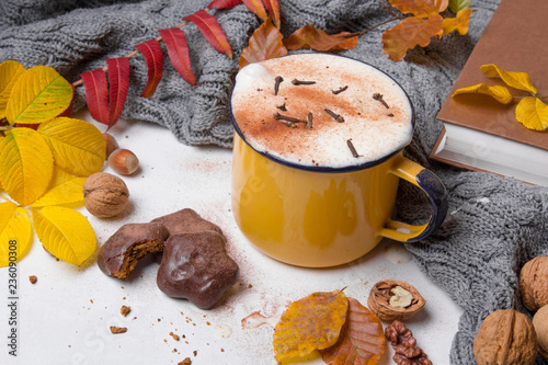 A mug of hot coffee surrounded by autumn leaves.