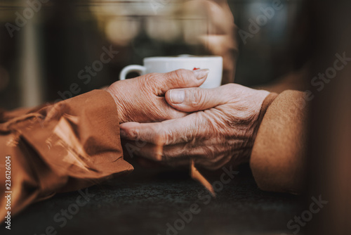 Warm and cozy. Close up of male and female arms with cup of coffee