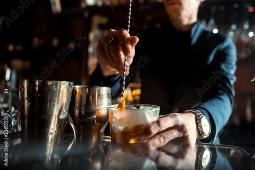 Expert Bartender is making cocktail at bar.