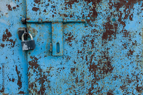 background fragment of an old rusty blue metal door with a padlock
