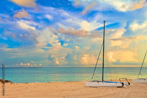 Catamaran on a tropical beach by the turquoise waters of the Caribbean sea, Freeport, Bahamas with stunning clouds in the background at sunset